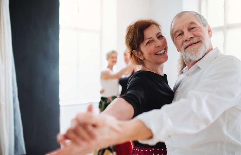 Woman smiling during ballroom dance lesson to relieve stress and improve mental health experiencing ballroom dance for mental health.